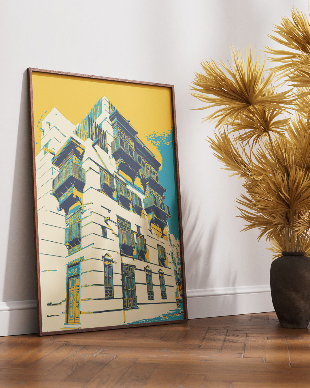 Framed artwork of al balad building on a wall next to a decorative plant.