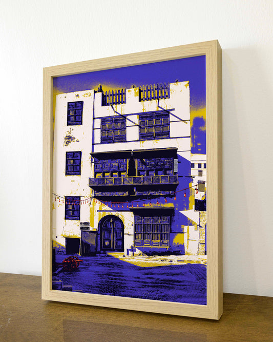 Framed artwork of a building with purple accents on a white wall.