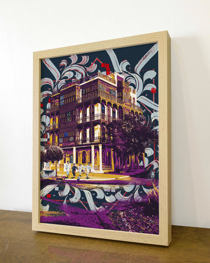 Framed artwork of a building with decorative elements on a wooden surface.