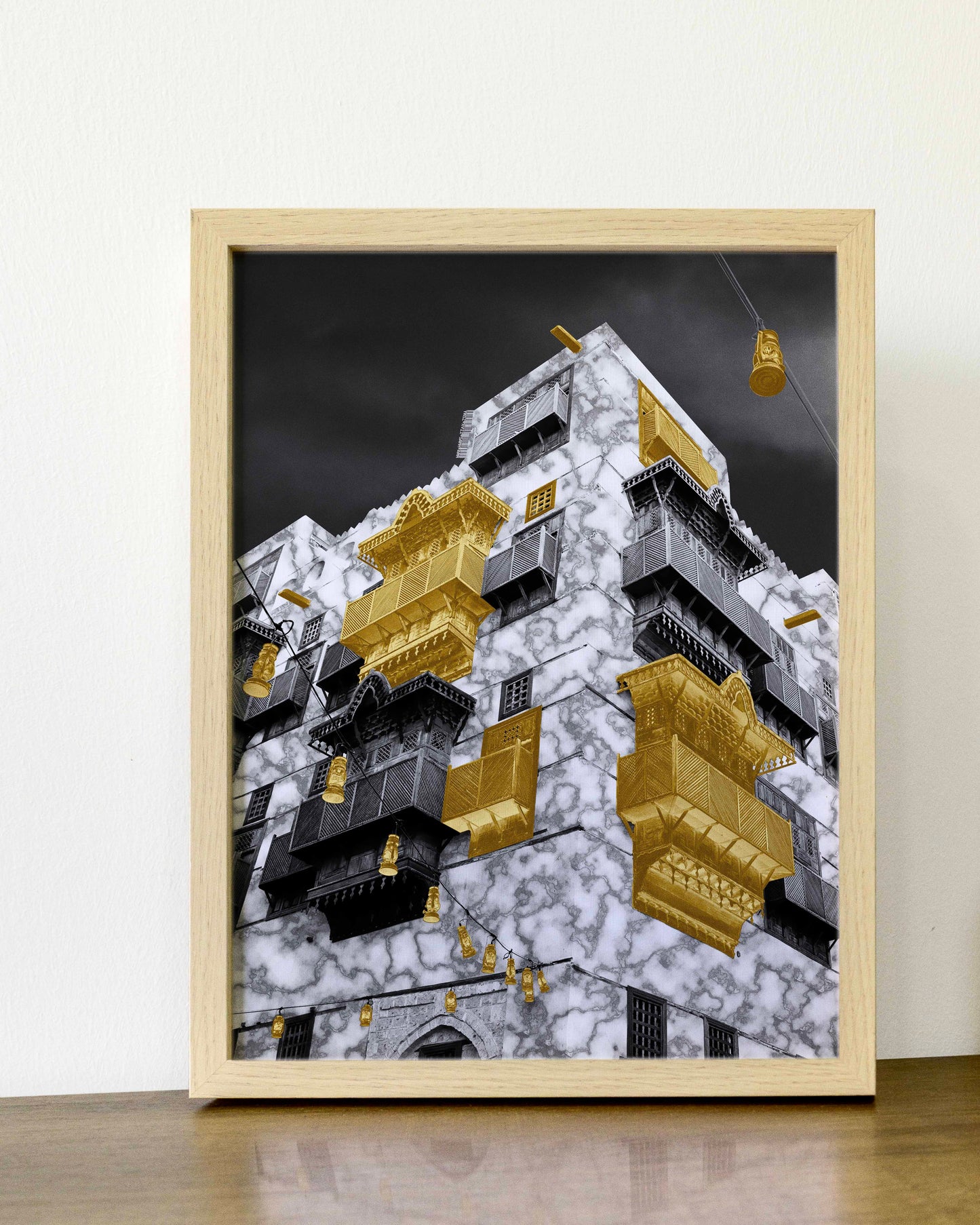 Framed artwork of a modern building with gold accents on a white wall.