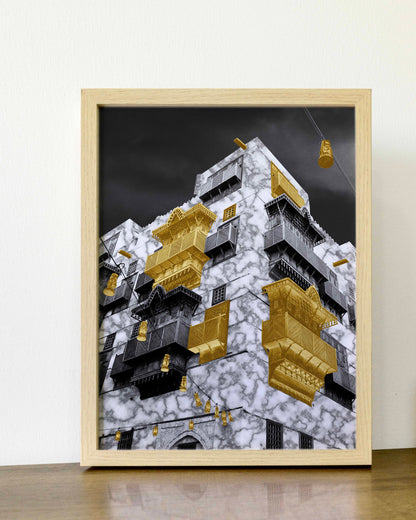 Framed artwork of a modern building with gold accents on a white wall.