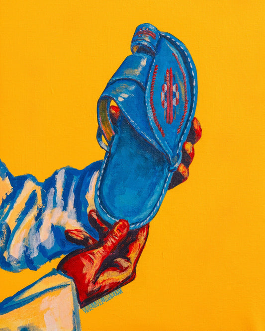 Blue sandal held by a hand against a yellow background